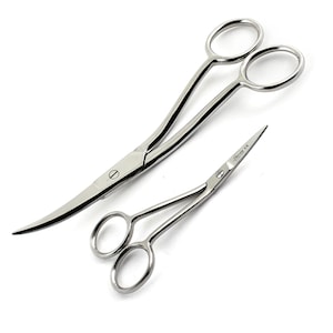 May include: Two stainless steel surgical scissors on a white background. One pair is curved with large finger loops, and the other is smaller and straight. The smaller scissors have the text "Stanny CE" printed on the blade.