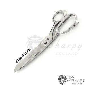 Könnte beinhalten: Glänzende, silberfarbene Schere mit einer Länge von ca. 20 cm. Sie hat große Fingerlöcher und scharfe, spitze Klingen. Der Text "Sharpy England" ist auf den Klingen zu sehen.