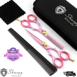 May include: A set of pink and gold-toned hair shears and a comb, with a black carrying case. The shears have pink handles and blades, with gold accents. A black comb and cleaning cloth are also included. The text "100% Satisfaction Guaranteed" is visible.