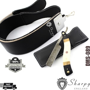 May include: A black leather razor strop with a black leather razor case and a straight razor with a patterned blade and a white and black handle. The razor has a red cross on the handle. The razor is labeled "Sharpy England" and "DMS-089".