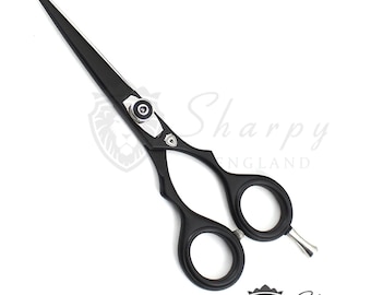 May include: Matte black hair cutting shears featuring a silver tension screw, a finger rest, and a small shield emblem on the pivot. The blades are black with a silver edge. The text Sharpy England is visible with a lion head logo.