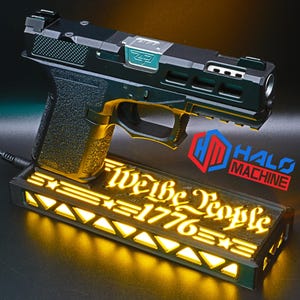May include: A black and green handgun with gold accents rests on a glowing rectangular base. The base features the text "We the People 1776" and a logo that says "Halo Machine". The handgun is connected to a power source.