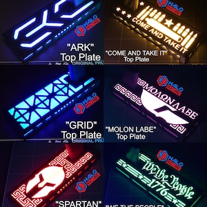 May include: A collection of illuminated top plates with various designs and text. The plates feature blue, white, red, and green LED lights. Text includes "ARK", "COME AND TAKE IT", "GRID", "MOLON LABE", "SPARTAN", and "WE THE PEOPLE 1776".