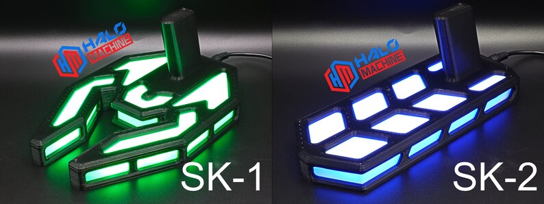 May include: Two black electronic devices with illuminated LED lights. One glows green, labelled "SK-1", and the other glows blue, labelled "SK-2". Both feature the "HALO MACHINE" logo. The devices have a geometric design and a rectangular base.