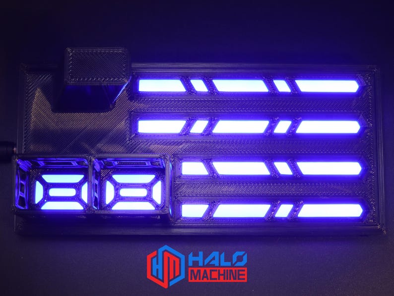 May include: A black rectangular device with blue neon lights. The device has multiple illuminated sections and the text "HALO MACHINE" in red and white. The device has a futuristic design.