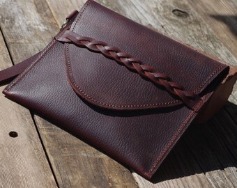 Rich brown leather bag with leather wrist strap and natural suede inside.  Braided leather closure. Full grain cow hide. Made in the USA