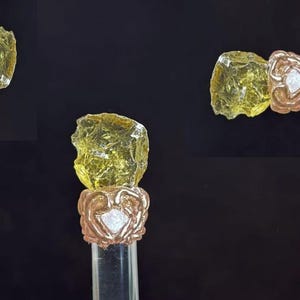 Puede incluir: Tapones de botella decorativos. Cada tap&oacute;n presenta un trozo de vidrio transparente, amarillo, de forma irregular, sobre una base de metal color cobre con un dise&ntilde;o floral. La base se asienta sobre un tallo cil&iacute;ndrico transparente.
