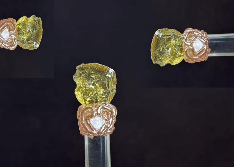 Puede incluir: Tapones de botella decorativos. Cada tap&oacute;n presenta un trozo de vidrio transparente, amarillo, de forma irregular, sobre una base de metal color cobre con un dise&ntilde;o floral. La base se asienta sobre un tallo cil&iacute;ndrico transparente.