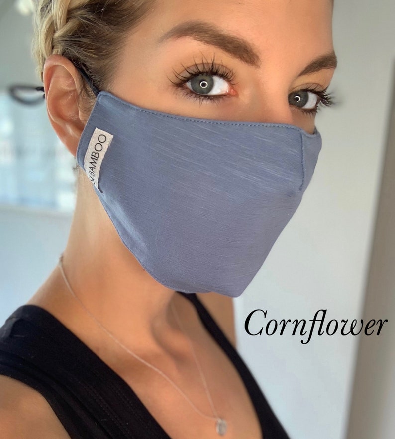 May include: A blue face mask made of bamboo fabric. The mask has a subtle texture and the words "BAMBOO" are printed on the side. The text "Cornflower" is written below the mask.
