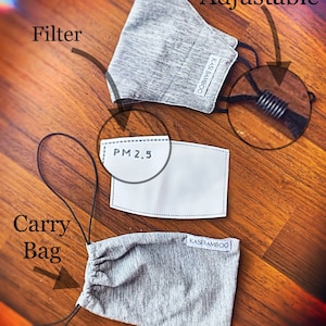 May include: A gray face mask with adjustable straps and a filter pocket. The mask is made of a soft, breathable fabric and comes with a carrying bag. The filter is labeled "PM 2.5".