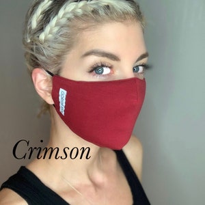 May include: A woman wearing a crimson face mask with the text "Kiss Bamboo" printed on it. The mask is made of a soft, breathable fabric.
