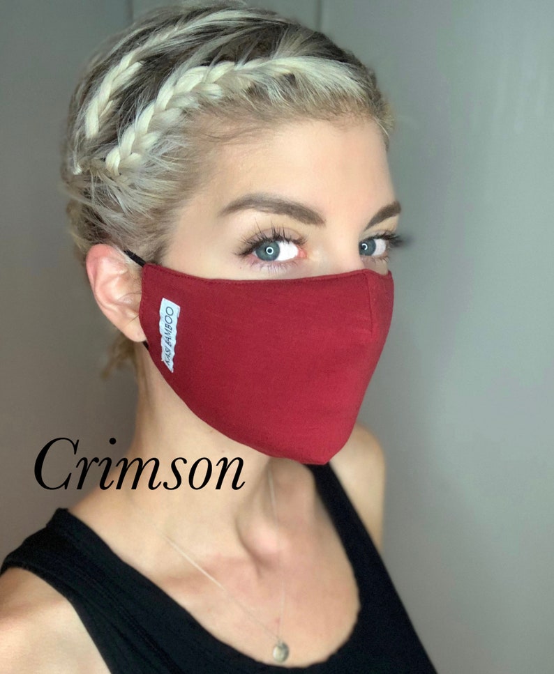 May include: A woman wearing a crimson face mask with the text "Kiss Bamboo" printed on it. The mask is made of a soft, breathable fabric.