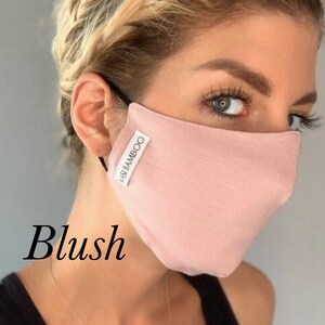 May include: A blush pink face mask made of bamboo fabric. The mask has the text "KASI BAMBOO" printed on it.