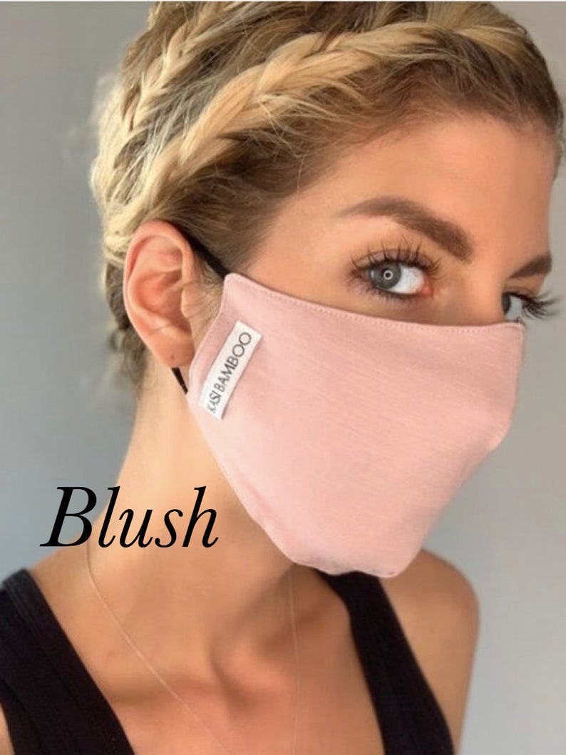 May include: A blush pink face mask made of bamboo fabric. The mask has the text "KASI BAMBOO" printed on it.