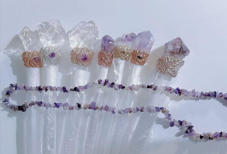 Puede incluir: Un surtido de varitas de cristal con detalles de amatista. Las varitas tienen puntas de cuarzo transparente y est&aacute;n adornadas con anillos envueltos en alambre y un collar de virutas de amatista. Los anillos son en tonos plateados y dorados.