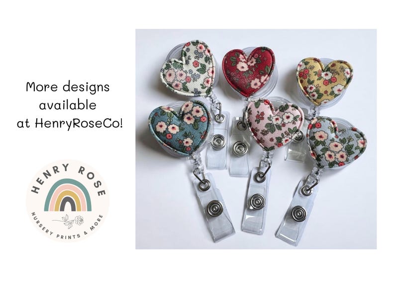 May include: Heart-shaped badge reels with floral fabric designs in various colors, including red, pink, and blue. The reels are attached to clear plastic retractable holders. Text on the image reads "More designs available at HenryRoseCo!"