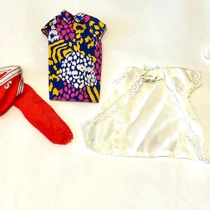 May include: Four doll outfits, including a red and white striped sweater, a white dress with lace trim, a colorful floral print dress with a white top, and a colorful abstract print shirt.