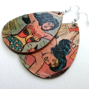 May include: A pair of teardrop-shaped earrings featuring a vintage Wonder Woman comic book image. The earrings are made of wood and have silver hooks.