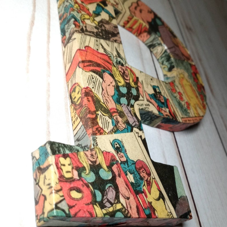 Puede incluir: Una gran letra "P" hecha de cart&oacute;n y cubierta de p&aacute;ginas de c&oacute;mics con superh&eacute;roes como Iron Man, Thor y Captain America. La letra es una adici&oacute;n brillante, colorida y divertida a la habitaci&oacute;n de un ni&ntilde;o.