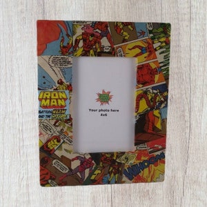 May include: A picture frame with a collage of comic book panels featuring Iron Man. The frame is made of wood and has a white mat. The text "Iron Man" and "Battles Klaw and the Wizard!" is visible on the frame. The text "Your photo here 4x6" is printed on the mat.