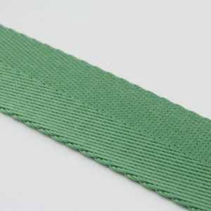 May include: A close-up of a green woven webbing strap.