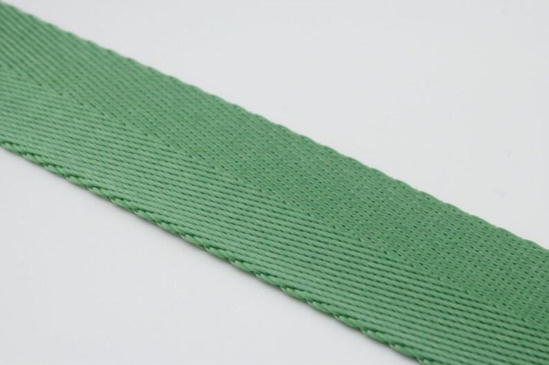 May include: A close-up of a green woven webbing strap.