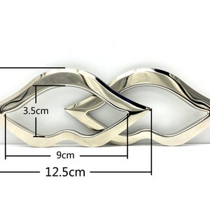 Op de afbeelding: Zilveren metalen dubbele oneindigheidssymbool met een hoogte van 6 cm, een breedte van 9 cm en een lengte van 12,5 cm.