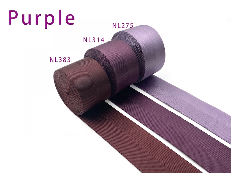 May include: Three rolls of purple nylon webbing tape arranged in a row. The rolls are labeled NL383, NL314, and NL275, showing shades ranging from deep dark purple to a lighter lavender tone. The text Purple is displayed in the upper left corner.