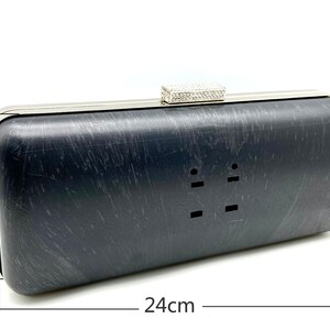 Pu&ograve; includere: Una pochette nera con cornice argentata e chiusura in strass. La pochette misura 24 cm per 10 cm.