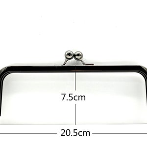 May include: A silver-toned metal purse frame with two round knobs on top. The frame measures 7.5 inches wide and 20.5 inches long.