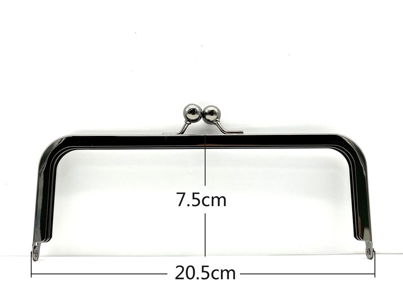 May include: A silver-toned metal purse frame with two round knobs on top. The frame measures 7.5 inches wide and 20.5 inches long.