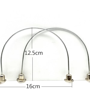 Può includere: Due maniglie in metallo argentato con un diametro di 12,5 cm e una lunghezza di 16 cm. Le maniglie sono in metallo sottile e hanno una forma arrotondata.