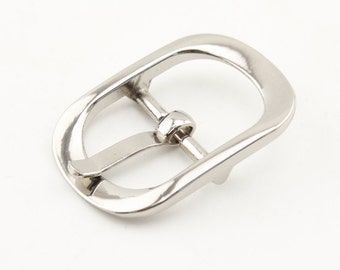 May include: A silver-toned metal buckle with a smooth, rounded oval shape. The buckle has a single prong for attaching to a strap.