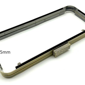 Pu&ograve; includere: Una cornice in metallo dorato per una borsa a mano con una chiusura in strass trasparente. La cornice misura 5 mm di larghezza.