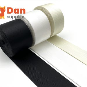 Pode incluir: Tr&ecirc;s rolos de fita em preto, branco e creme. A fita &eacute; um tecido tecido com uma superf&iacute;cie texturizada. Os rolos est&atilde;o dispostos em um padr&atilde;o escalonado.