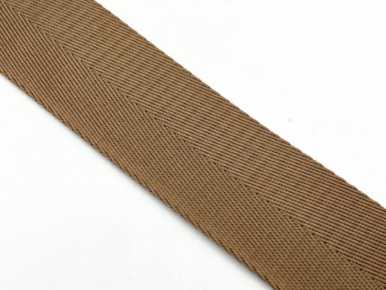 May include: A brown herringbone ribbon with a subtle sheen. The ribbon is woven with a tight, even weave.
