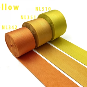 May include: Three rolls of woven nylon webbing in a gradient of yellow and orange shades. The rolls are labeled NL342, NL351, and NL510, with the text Yellow displayed at the top. The fabric features a tight, durable weave with a smooth texture.