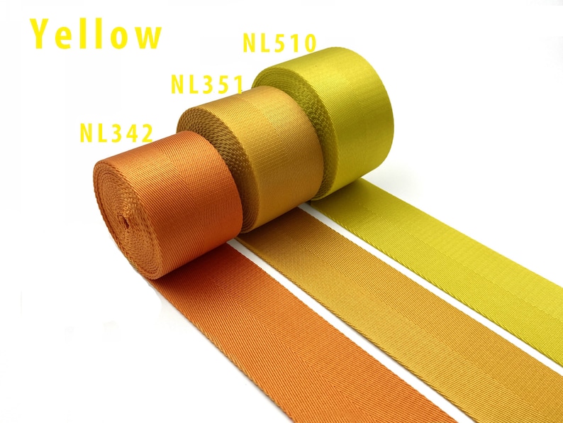 May include: Three rolls of woven nylon webbing in a gradient of yellow and orange shades. The rolls are labeled NL342, NL351, and NL510, with the text Yellow displayed at the top. The fabric features a tight, durable weave with a smooth texture.