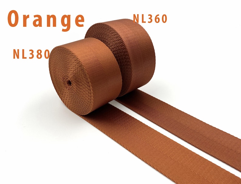May include: Two rolls of orange nylon webbing tape are displayed, each featuring a distinct herringbone weave pattern. The text "Orange" is visible at the top left, with "NL380" below it and "NL360" positioned near the second roll of webbing.