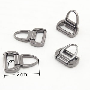 Puede incluir: Tres cierres metálicos plateados con un anillo en D en un extremo y un gancho en el otro. Los cierres miden aproximadamente 2 cm de largo y 1 cm de ancho.