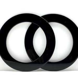 May include: Two black plastic rings, interlocked, with a smooth, glossy finish.