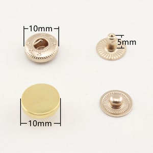 Puede incluir: Broches de presión metálicos de color dorado, de 10 mm de diámetro, con un botón de 5 mm. Los broches de presión se muestran en dos configuraciones: una con un borde decorativo y otra con una superficie lisa.