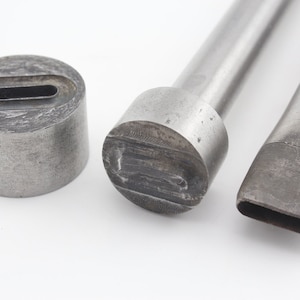 Op de afbeelding: Drie metalen ponsgereedschappen voor lederbewerking. De gereedschappen zijn gemaakt van staal en hebben een zilveren afwerking. De gereedschappen worden gebruikt om gaten in leer te maken voor stiksels of andere decoratieve doeleinden.