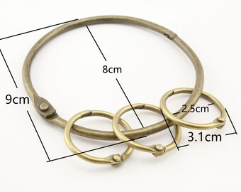 Könnte beinhalten: Drei Schlüsselringe aus Messing in verschiedenen Größen. Der größte Ring hat einen Durchmesser von 9 cm und einen Umfang von 8 cm. Der mittlere Ring hat einen Durchmesser von 3,1 cm. Der kleinste Ring hat einen Durchmesser von 2,5 cm.