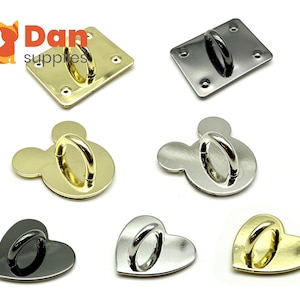 May include: Assortment of six metal hardware pieces in gold, silver, and black. The pieces are shaped like a square, a heart, and Mickey Mouse's head. Each piece has a metal ring attached.