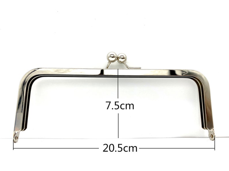 May include: Silver-toned metal purse frame with two round metal clasps. The frame measures 7.5 inches wide and 20.5 inches long.
