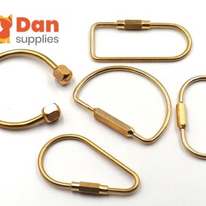 May include: Five gold-colored key rings with different shapes and sizes.  The key rings are made of metal and have a polished finish.