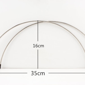 May include: Two silver metal hoops with black plastic end caps. The hoops are 16 cm tall and 35 cm wide.