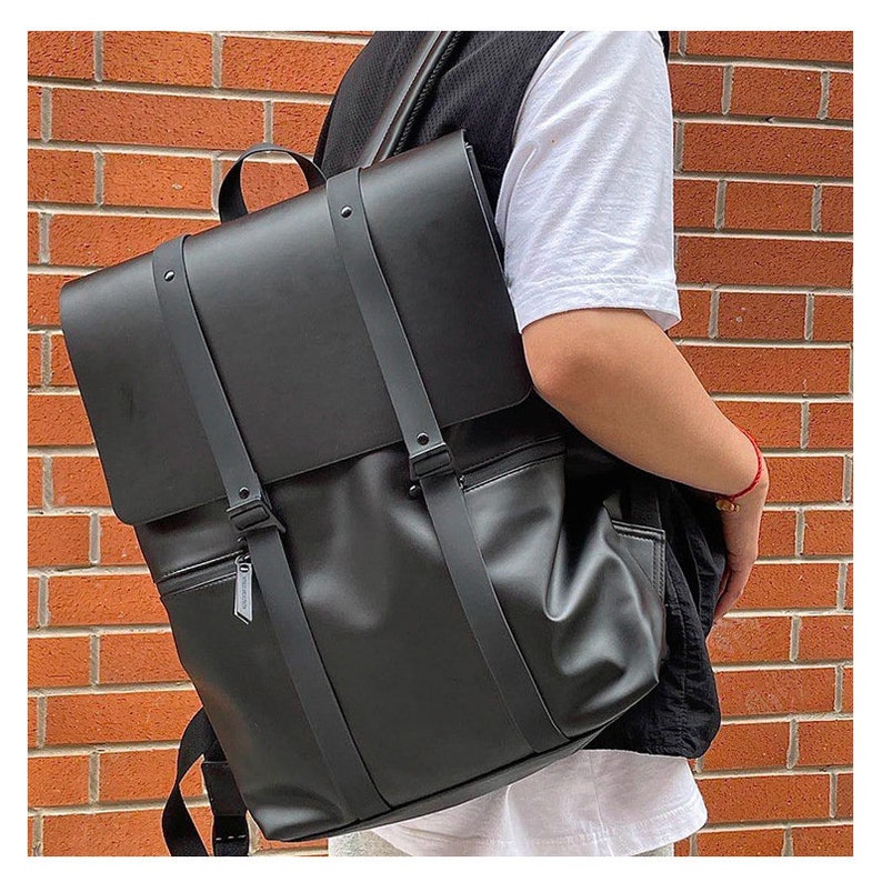 May include: A black leather backpack with adjustable straps and a zippered pocket. The backpack has a flap with a buckle closure.