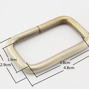 May include: A gold-toned metal D-ring with rounded edges. The ring measures 1.9 inches by 2.9 inches and 3.8 inches by 4.8 inches.